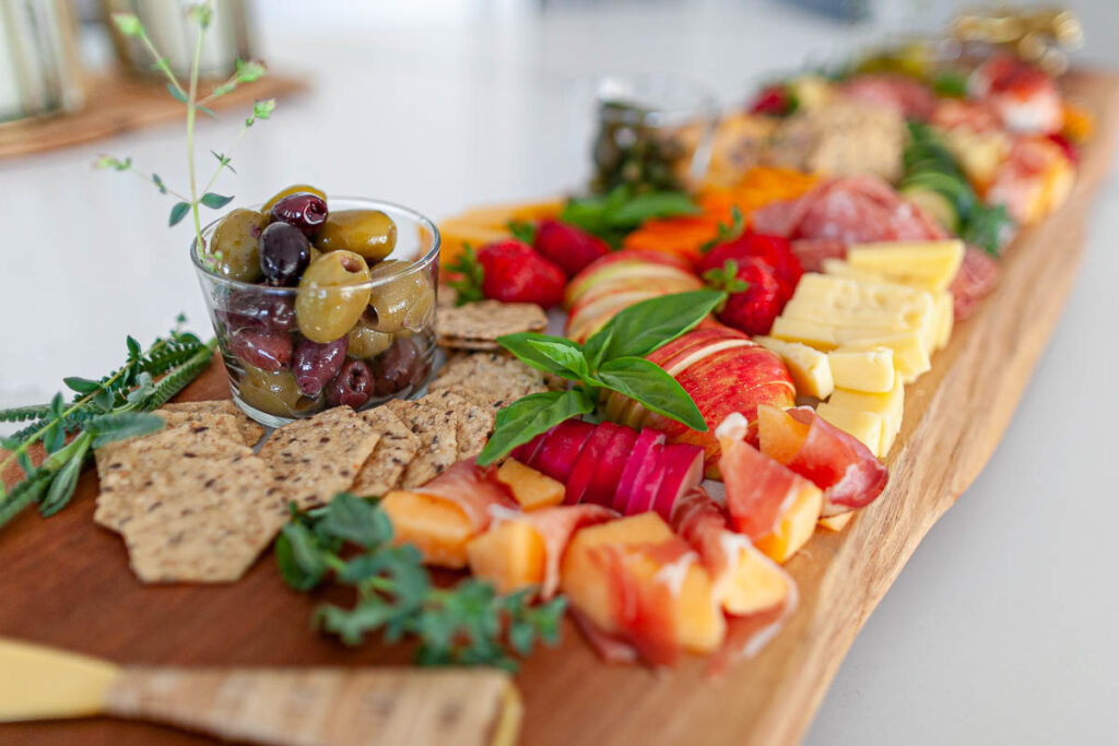 olives, crackers, fresh fruit, and fresh herbs on a charcuterie board